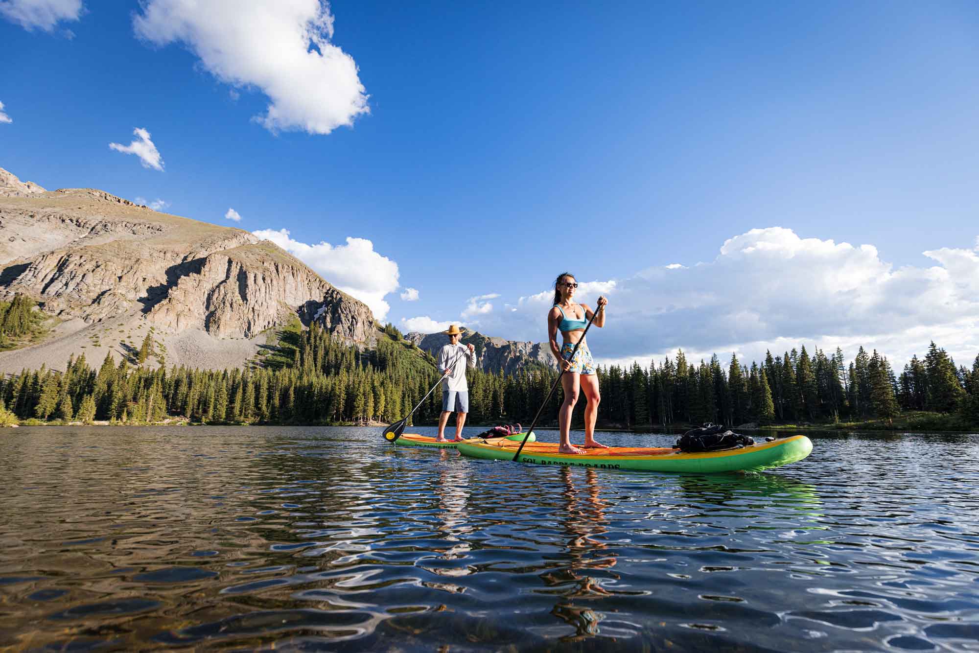 Two paddleboarders with a mesa rising in the background