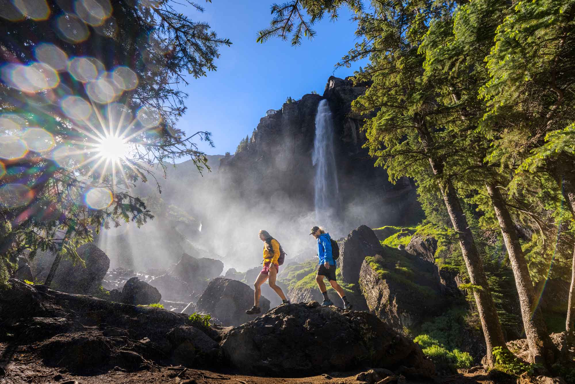 A couple hiking Bridal Veil Falls in Telluride in the setting sun