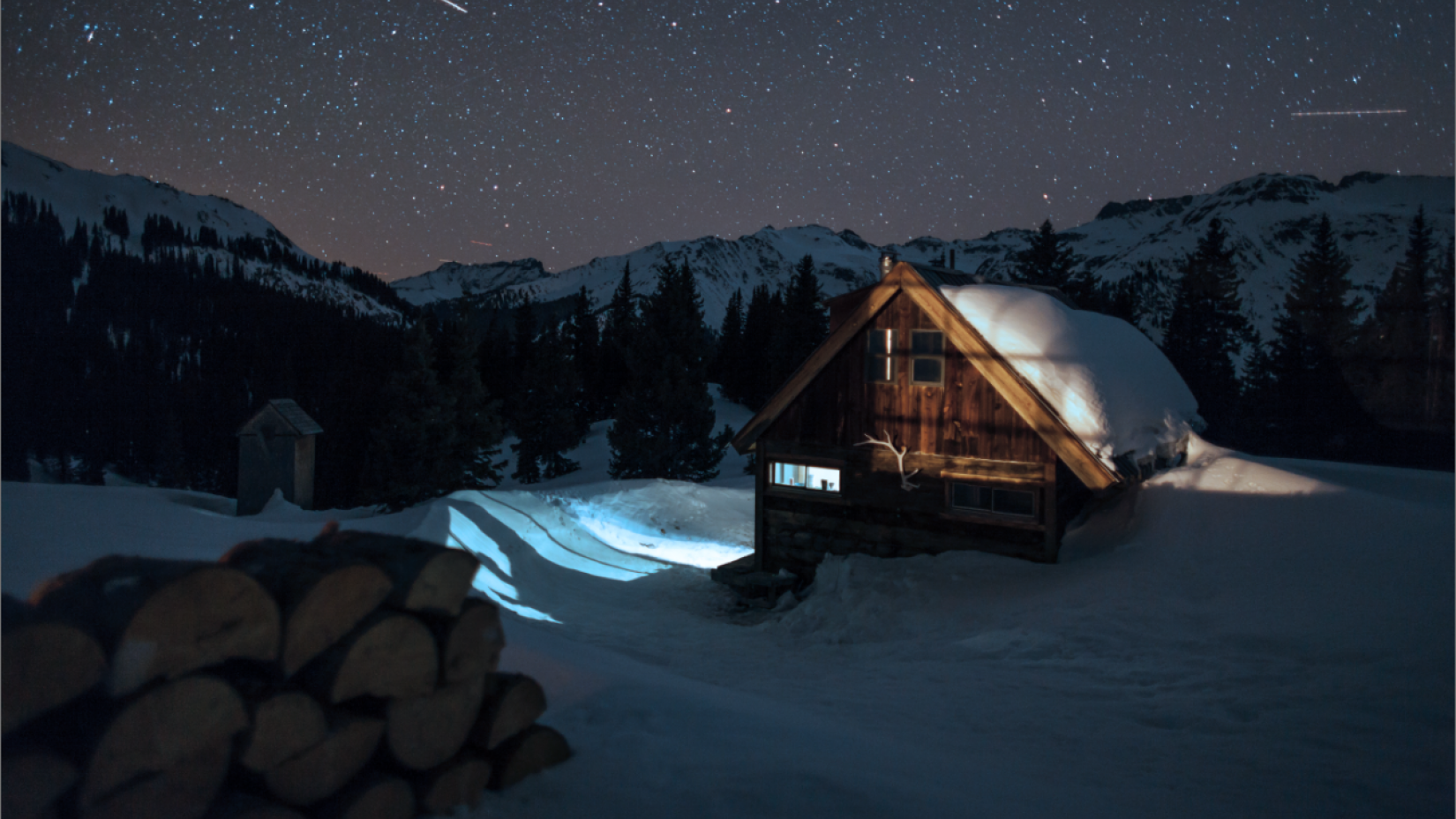 A snow-covered cabin under a starry night sky