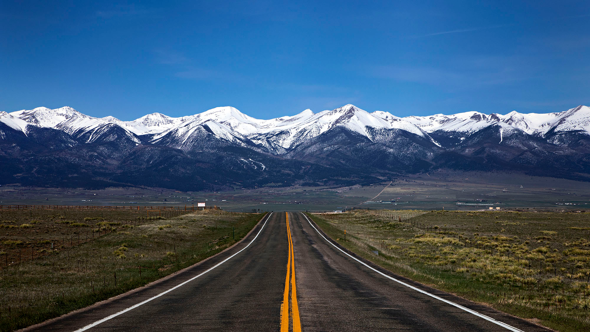 A road heading to the snowcapped Sangre de Cristo Mountains on the Frontier Pathway scenic byway in Westcliffe, Colorado