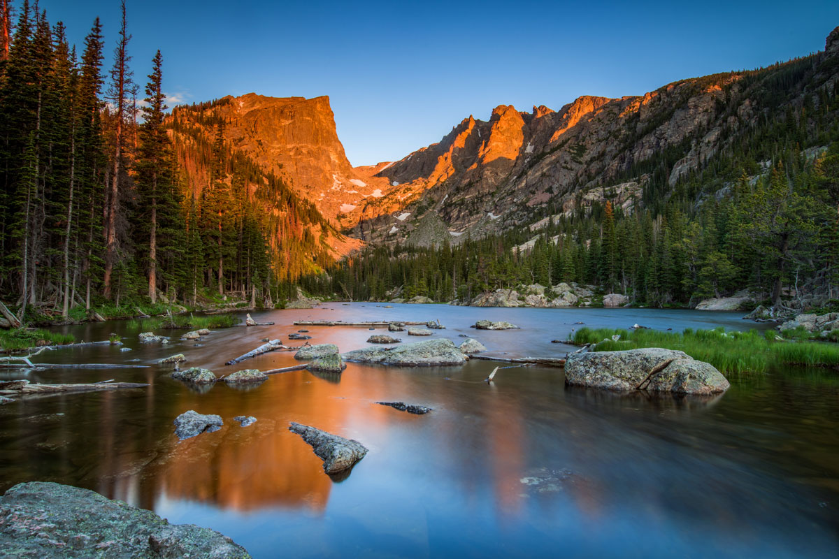 A high-alpine lake below peaks with alpenglow at Rocky Mountain National Park