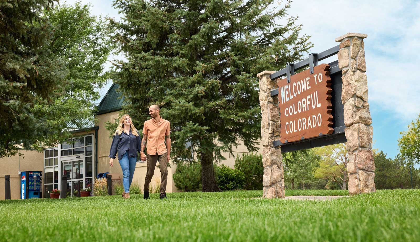 Two people walk in front of the Colorful Colorado sign at the Burlington Welcome Center