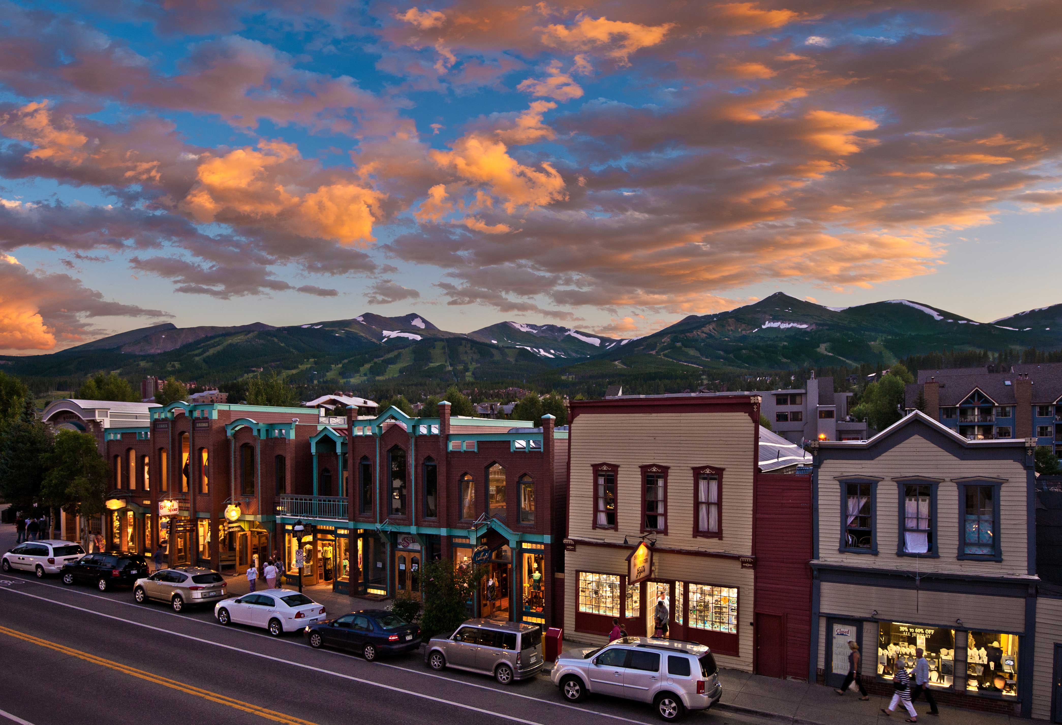 The sunset paints the clouds pink and warm lights from inside the cozy shops of Main Street Breckenridge spill out on the sidewalk.