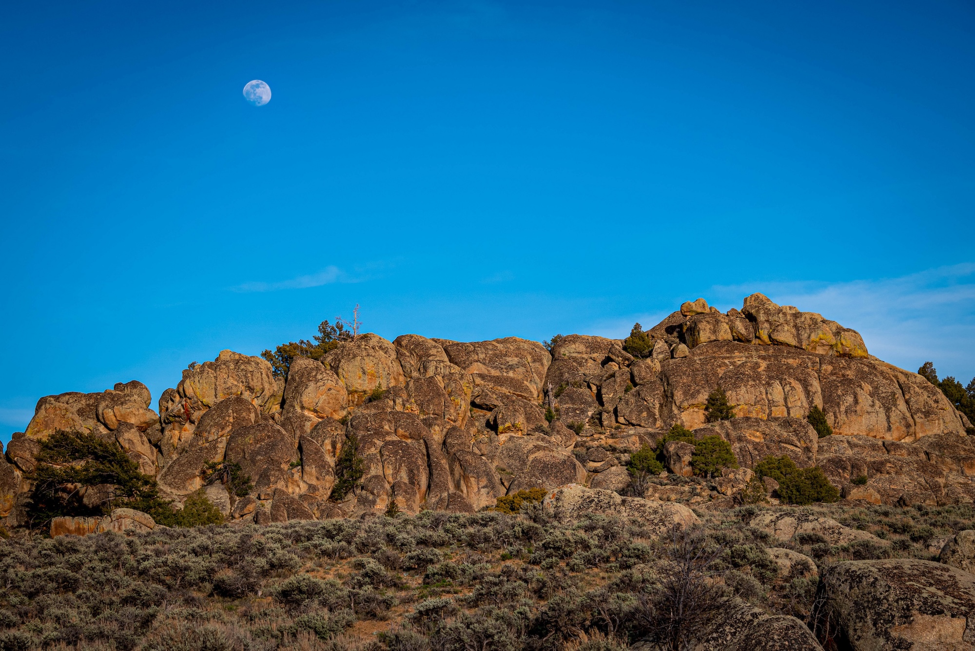 Rugged rock formations with the moon in the sky above in Gunnison, Colorado.