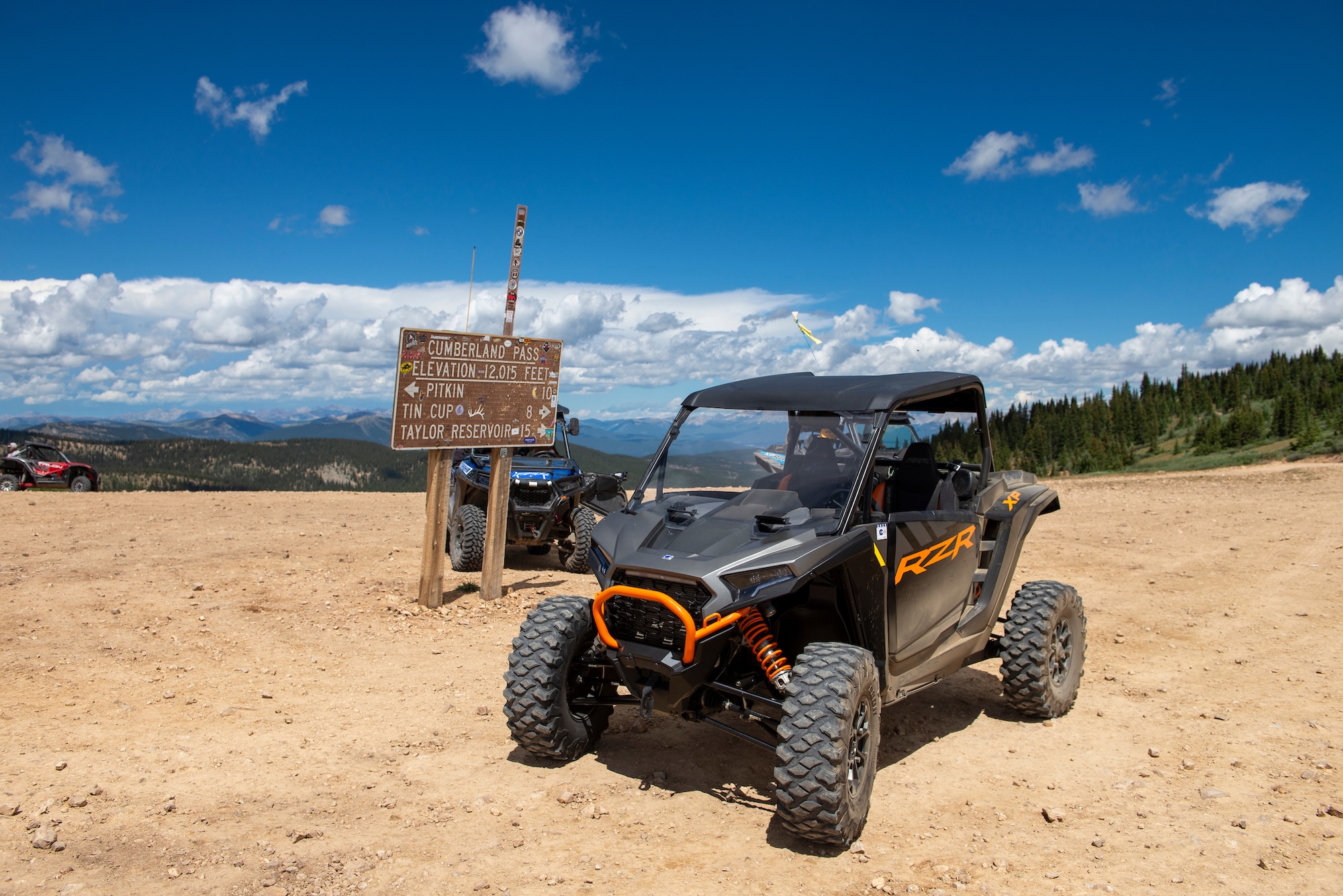 Off-road vehicle parked near a Cumberland Pass sign on a high alpine mountain pass with expansive views in Pitkin, Colorado.