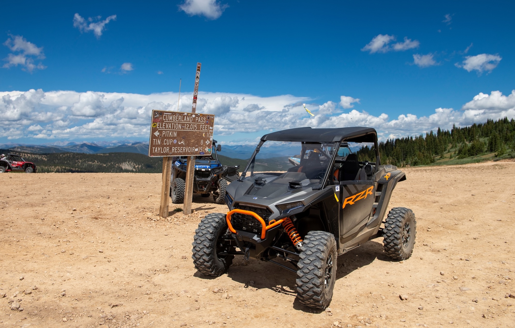 Off-road vehicle parked near a Cumberland Pass sign on a high alpine mountain pass with expansive views in Pitkin, Colorado.