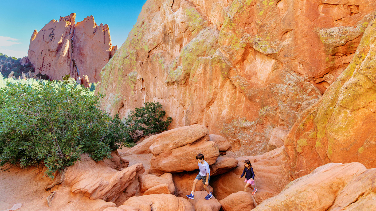 Two kids walk amid red-rock formations under a "Colorado Vibrante" headline