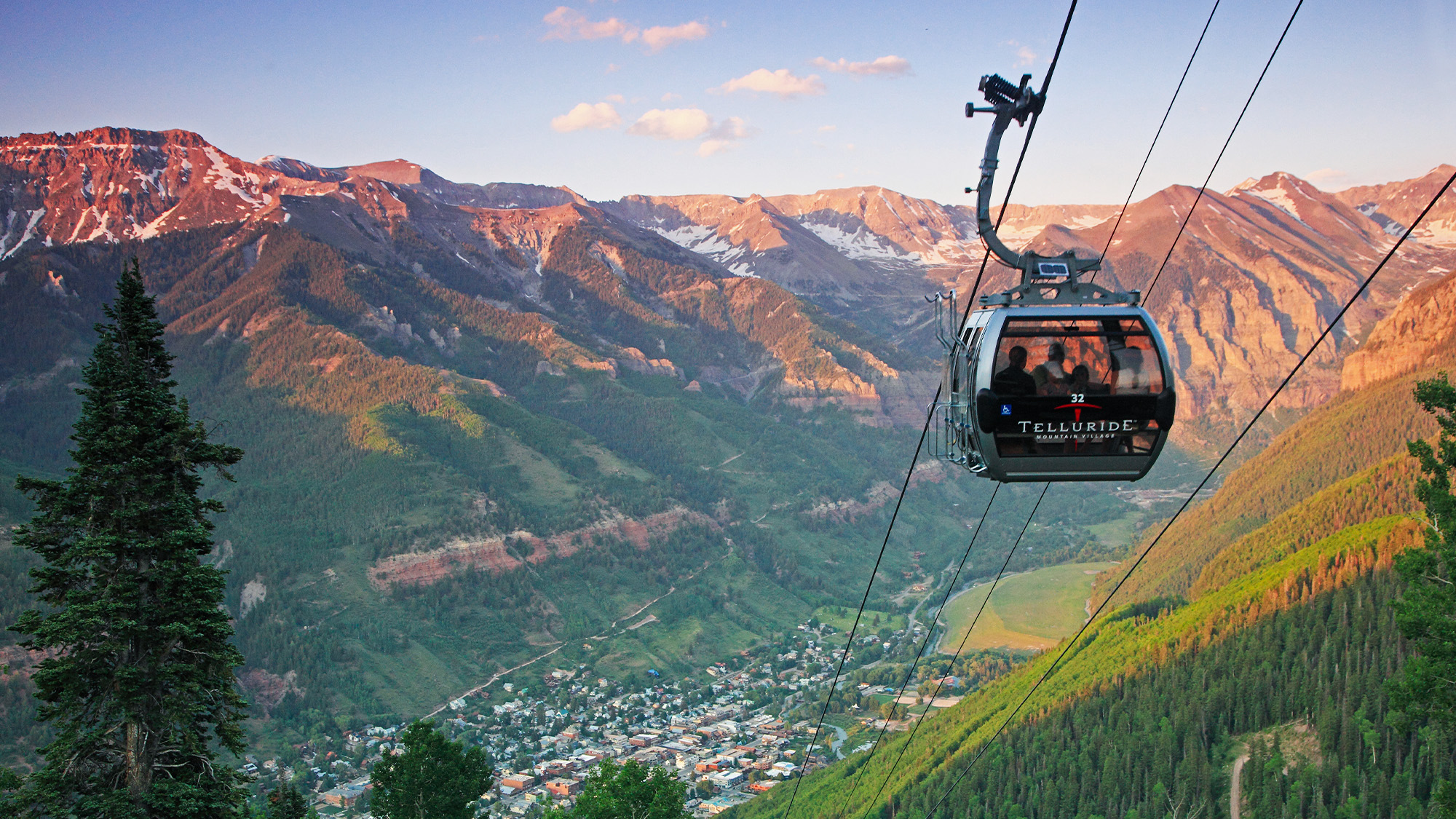 Gondola ascending above Telluride, Colorado, with mountain peaks in the background at sunset